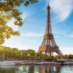 Eiffel Tower in Paris with boats on the river and green trees