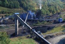 $700M Coal Play Rattles Energy Crowd Industrial coal processing facility with conveyor belts and smoke stack