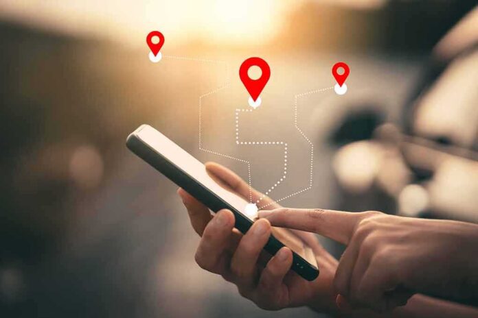 shutterstock_1631344318 Person using a smartphone with location markers displayed on the screen