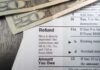 Ghost Firms Grab $6B — Clock Ticks Close-up of tax refund form with cash on a wooden surface