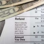 Ghost Firms Grab $6B — Clock Ticks Close-up of tax refund form with cash on a wooden surface