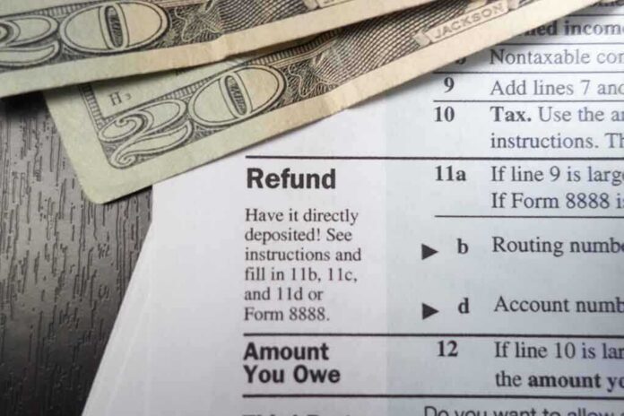 shutterstock_173624585 Close-up of tax refund form with cash on a wooden surface