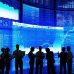 Sanders’ AI Power Grab Sparks Wall Street Panic Silhouetted business professionals in front of digital stock market displays