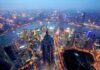 Pentagon Bombshell Blacklists Alibaba, BYD Aerial view of Shanghais skyline at night with illuminated buildings and a river