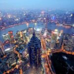 Pentagon Bombshell Blacklists Alibaba, BYD Aerial view of Shanghais skyline at night with illuminated buildings and a river