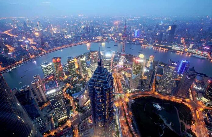 shutterstock_219709417 Aerial view of Shanghais skyline at night with illuminated buildings and a river