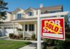 A house with a Sold sign in the front yard