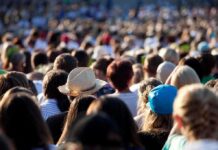 Chaos Erupts at TPUSA Summit A large crowd of people gathered outdoors, with various hats and hairstyles visible