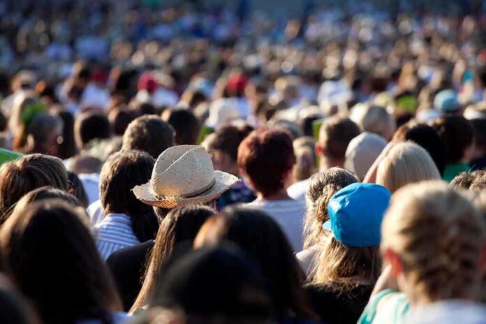 A large crowd of people gathered outdoors, with various hats and hairstyles visible