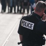 Active Killer Cornered In Midland Police officer in uniform communicating with a crowd in an urban setting