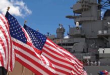 Barracks Horror Exposed — System Shrugged American flags in front of a naval ship under a blue sky