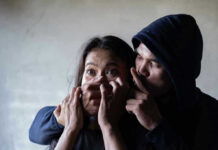 AI Kidnaps By Phone Now Man holding womans mouth, gesturing silence.
