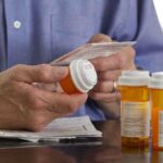 Founder Jailed After 37 Million Pills Person holding a prescription bottle and reading medical instructions