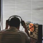 FBI Wire Inside Newsom’s Circle Person wearing headphones listening to a reel-to-reel tape recorder