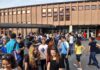 Nine Overdoses. Board Says No Teacher Testing A large group of students socializing outside a school building