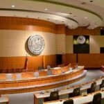 White House Firebrand Drops ‘Communist’ Bomb Interior view of a government chamber with wooden paneling and seating