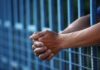 Lenient Sentence Ignites Fury Close-up of clasped hands resting on a blue fence