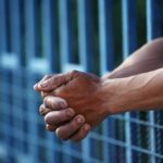 Lenient Sentence Ignites Fury Close-up of clasped hands resting on a blue fence