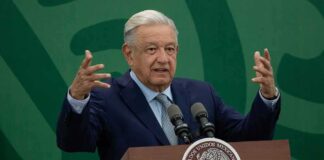 man at podium speaking with raised hands