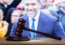 judge's gavel on desk with blurred suited man in background