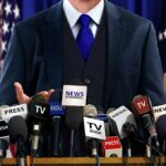 Musk Drag Triggers DOJ Cloud Over Newsom A speaker at a press conference with multiple microphones in front of them