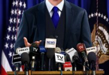 Musk Drag Triggers DOJ Cloud Over Newsom A speaker at a press conference with multiple microphones in front of them
