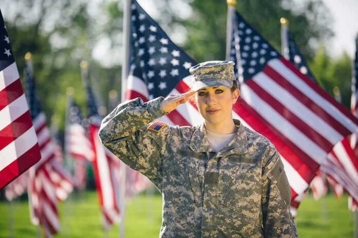 shutterstock_1081070213-1 Soldier saluting among American flags