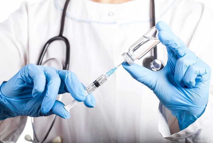 shutterstock_1310971853 Healthcare worker drawing vaccine from vial with syringe