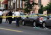 Police at urban street crime scene with yellow tape around parked cars