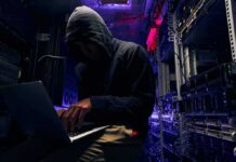 Hijacked Home Routers Fueled Federal Breach Hooded person using a laptop in a dark server room