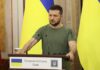 Man at a podium with Ukrainian flags