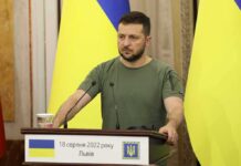 Man at a podium with Ukrainian flags