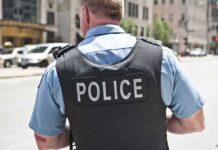 Burglar Shot — Then Demands Millions Police officer in uniform from behind on a city street