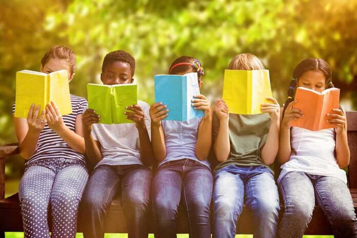 shutterstock_307383305 Children sitting on a bench reading colorful books outdoors