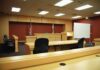 Solitary In, Date Out: Diddy Turmoil Interior view of an empty courtroom with wooden furniture and American flags
