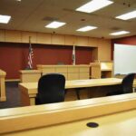 Solitary In, Date Out: Diddy Turmoil Interior view of an empty courtroom with wooden furniture and American flags