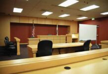 Solitary In, Date Out: Diddy Turmoil Interior view of an empty courtroom with wooden furniture and American flags