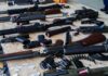 Anonymous Cremation Payment Sparks Outrage Assorted firearms and ammunition laid out on a wooden table