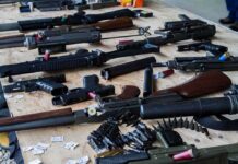 Anonymous Cremation Payment Sparks Outrage Assorted firearms and ammunition laid out on a wooden table