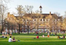 China Ties Ignite Federal Probe Into Top Universities Students relaxing on a campus quad in front of a brick academic building