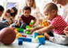 Judge Slams Daycare Bans On Vaccines Karyn Polito with toddlers building blocks on a play mat