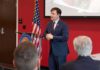 Speaker in a navy suit addressing an audience at a podium