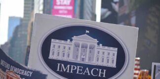 Protest crowd holding an impeach sign with the White House emblem