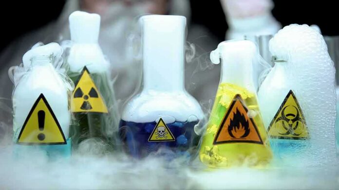 shutterstock_1537370753 laboratory flasks with hazard symbols and colorful liquids