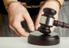 Handcuffed person behind judge's gavel