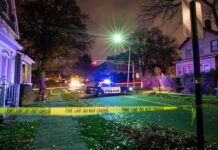 Killer Creeps In – Doctor Slain In Bed Police car blocks residential street at night behind caution tape