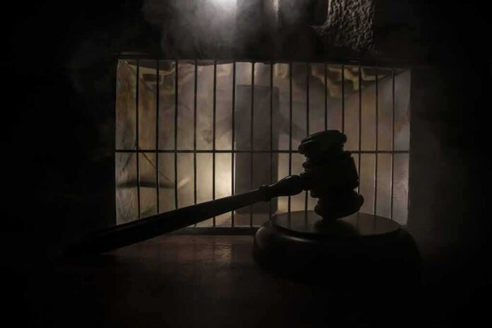 shutterstock_1809917053 Judge’s gavel in silhouette before prison bars