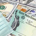 Election Shock Play: $500 Health Rebates U.S. Treasury check with face mask on pile of hundred-dollar bills