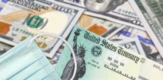 U.S. Treasury check with face mask on pile of hundred-dollar bills
