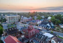 Quiet Town vs. Big Tech Payout Small town at sunrise with historic buildings and tree-lined streets